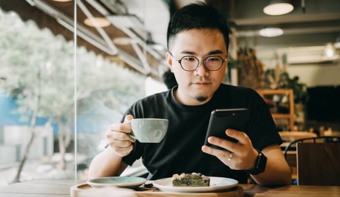 Mann beim Essen mit Handy, auf dem Norton 360 Standard gestartet wird